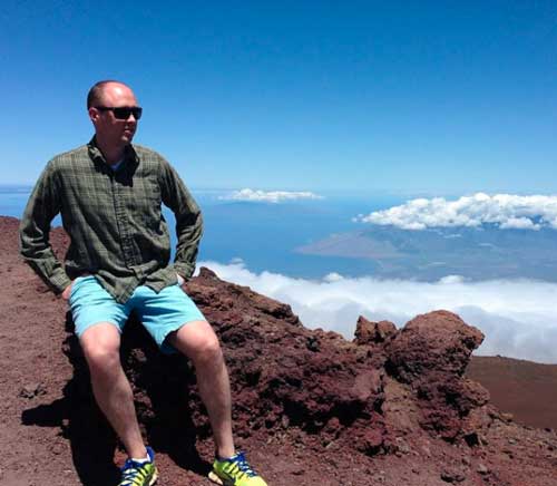 Tyler Tervooren on top of a mountain sitting down on rocks