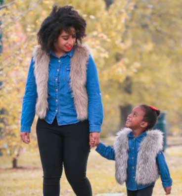 single black motherhood founder and daughter walking in the park