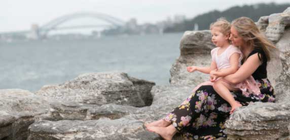 single mother with daughter sitting on the rocks